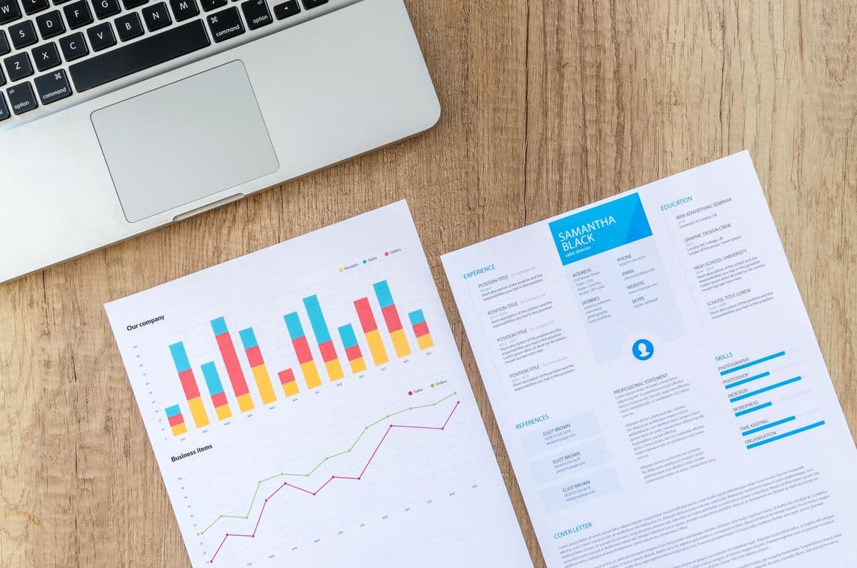 Financial charts and business plan documents beside a laptop