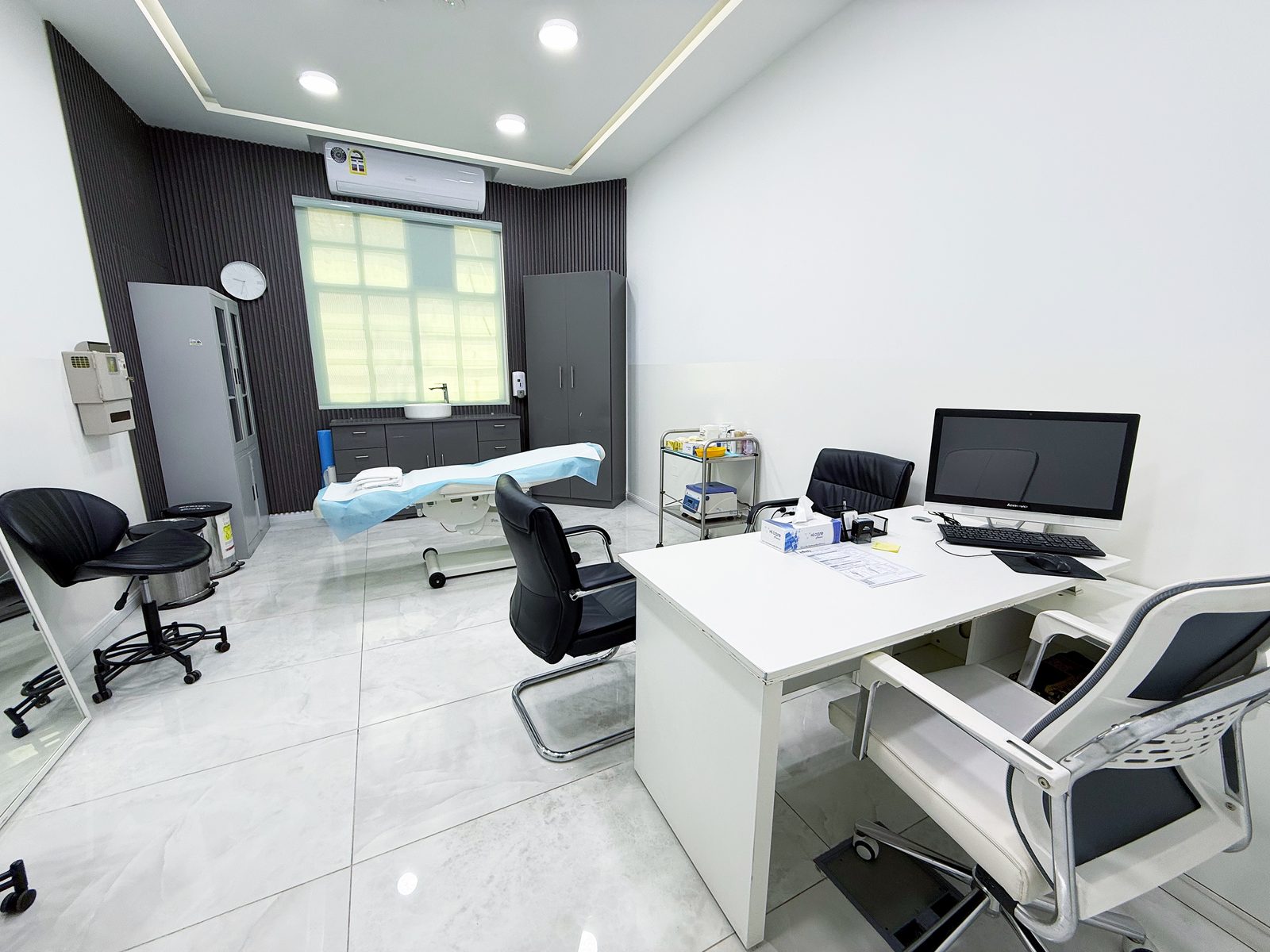 Consultation room with examination couch and desk in a poly clinic in Jumeirah, Dubai