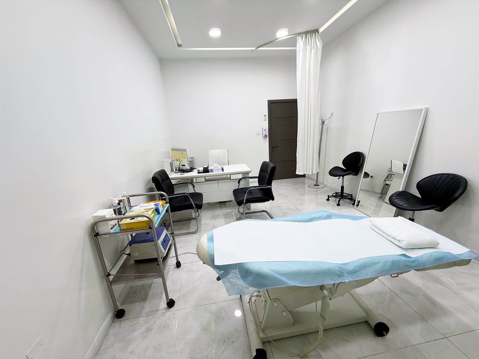Consultation room with examination bed and privacy curtain in a poly clinic in Jumeirah, Dubai