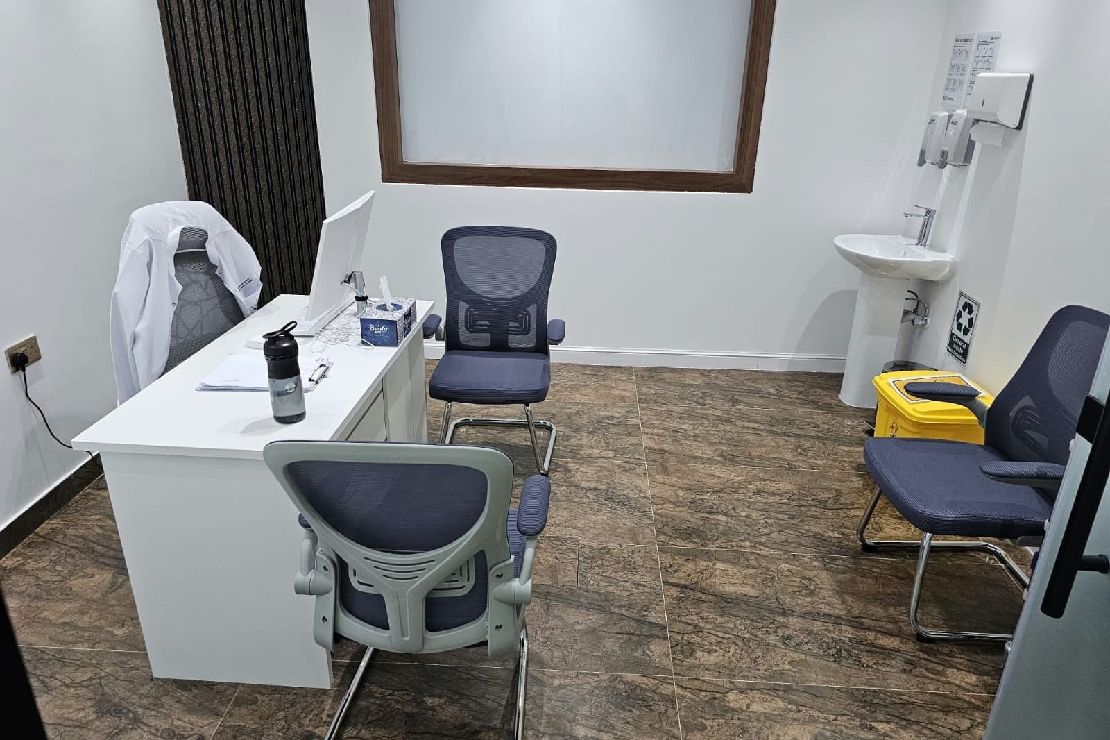 Doctor's consultation room with desk and patient seating in a medical centre in Al Danah, Abu Dhabi